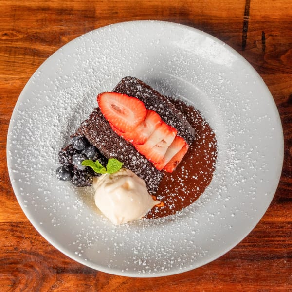 Chocolate brownie with strawberries, blueberries, blackberries, mint, and vanilla ice cream.